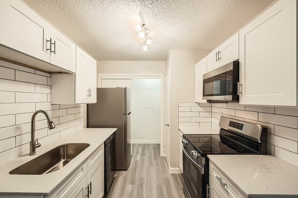 A kitchen with white cabinets and a black stove top oven.