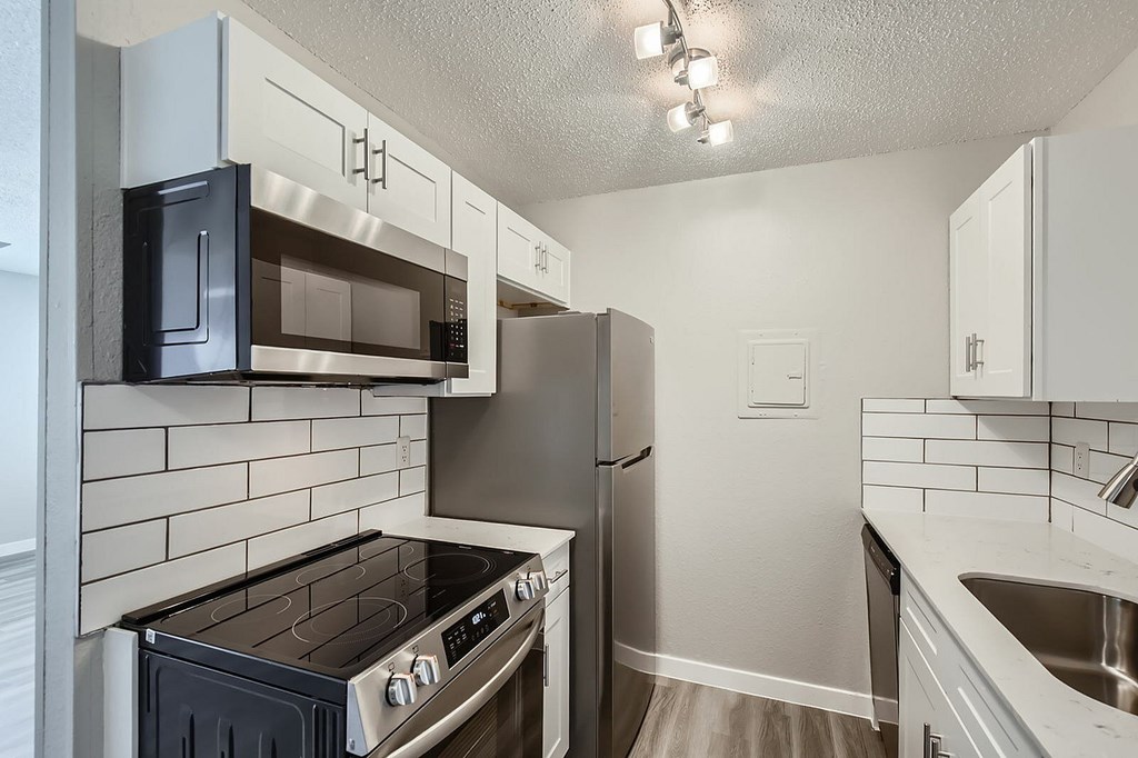 A kitchen with a black stove top oven and a black microwave above it.