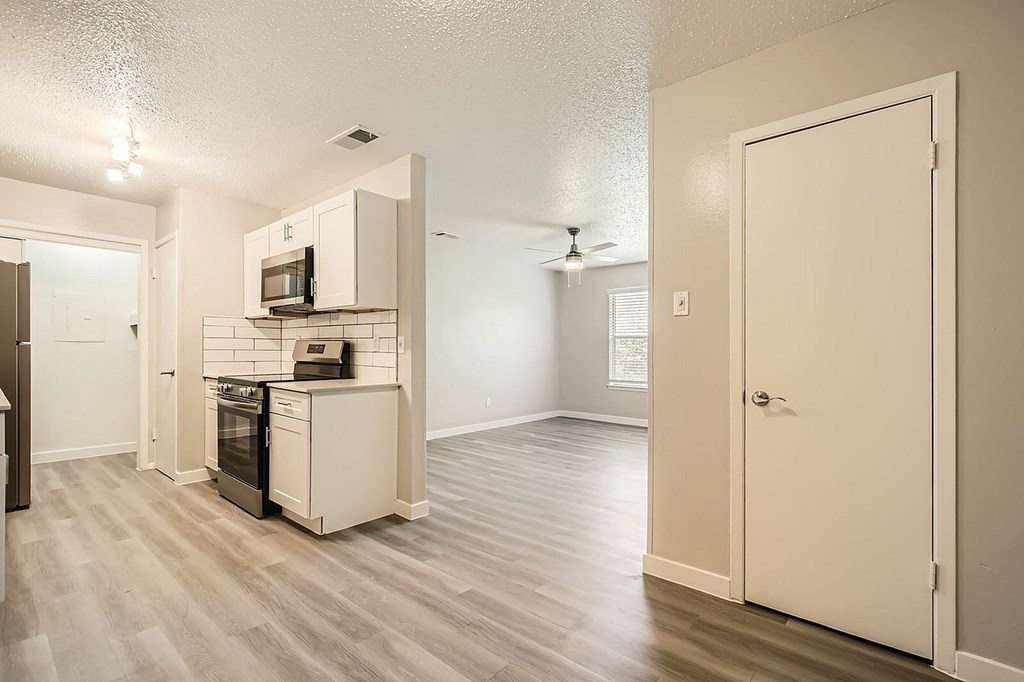 A kitchen with a microwave on top of the fridge and a stove and oven below.