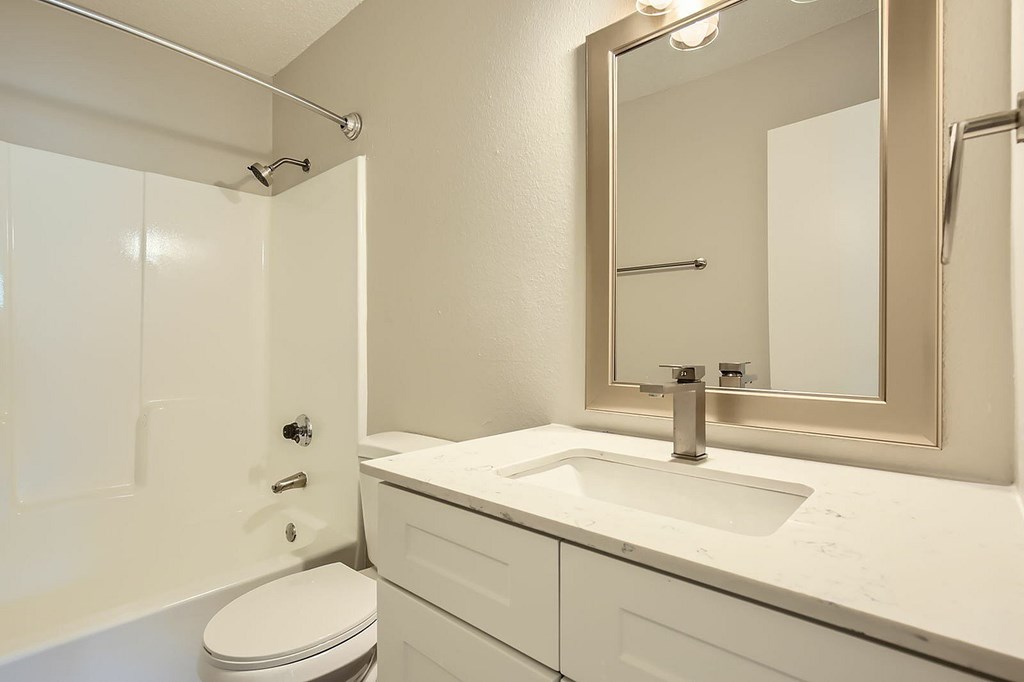 A white bathroom with a toilet, sink, and mirror.