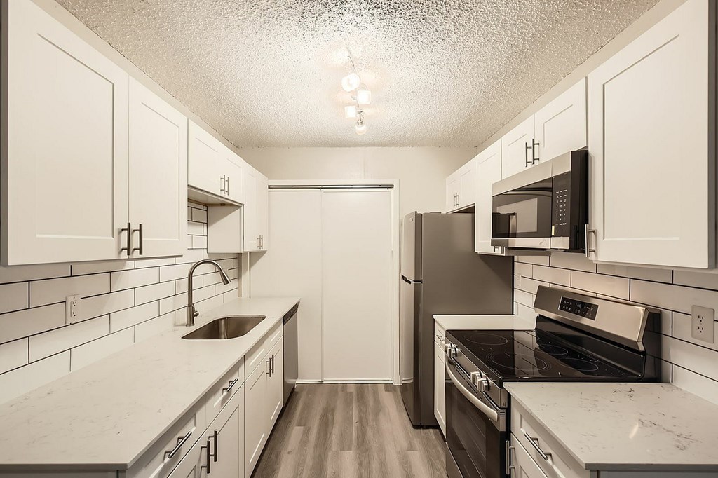 A kitchen with black appliances and white cabinets.