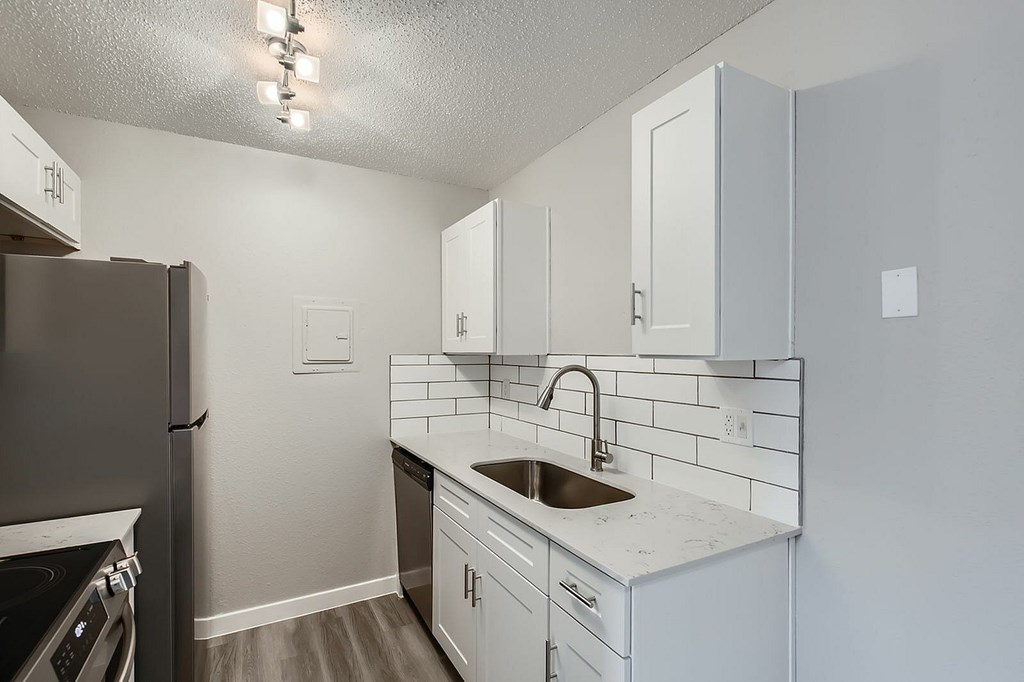 A kitchen with white cabinets and a black refrigerator.