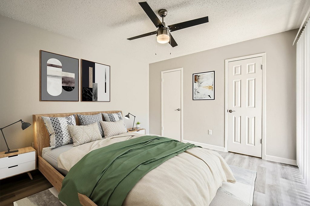 A bedroom with a bed, a ceiling fan, and a green blanket.