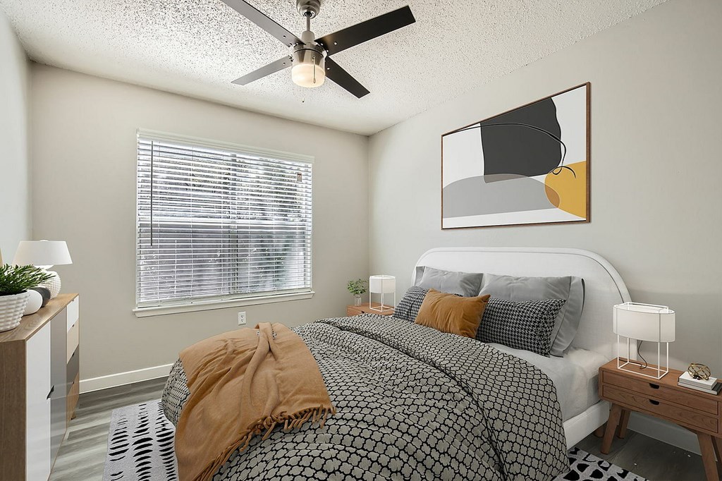 A bedroom with a bed, nightstands, and a ceiling fan.