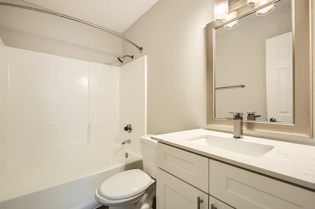 A white bathroom with a toilet, sink, and mirror.