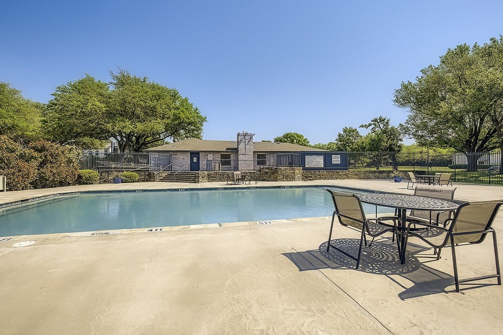 A pool with a table and chairs in front of a building.