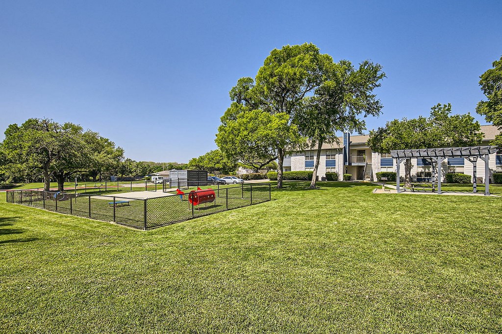 A tennis court is surrounded by a fence and trees.