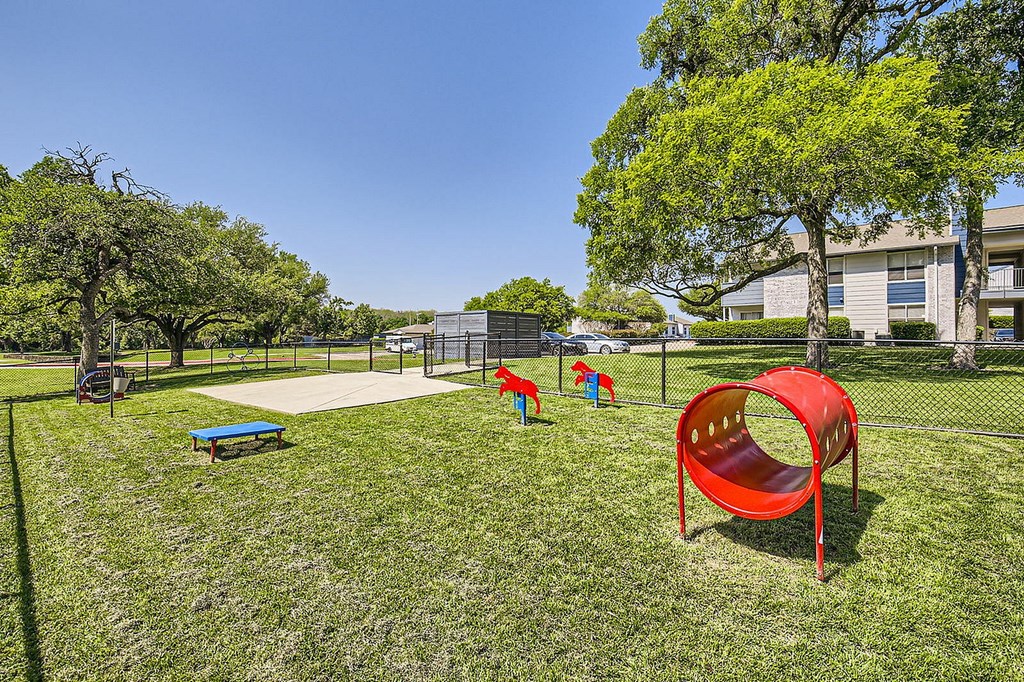 A playground with a red slide and a blue bench.