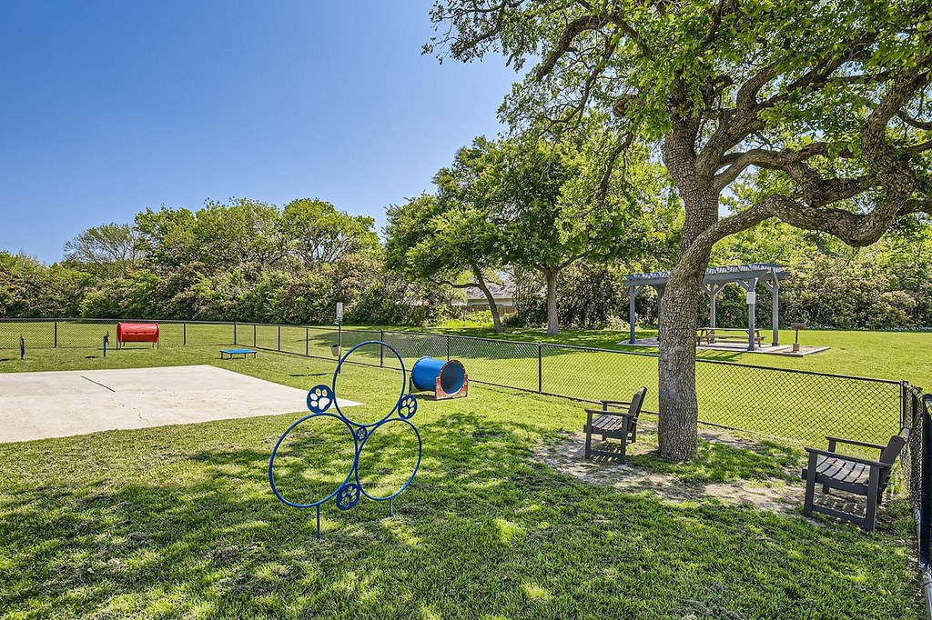 A playground with a slide, swings, and a tree.