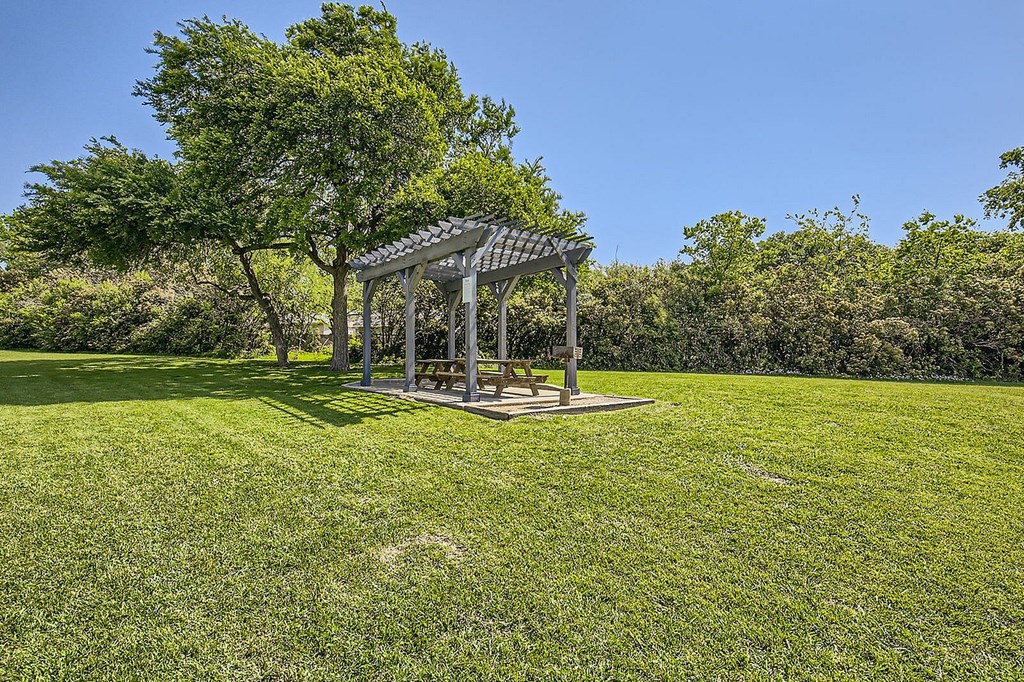 A gazebo sits in the middle of a grassy field.