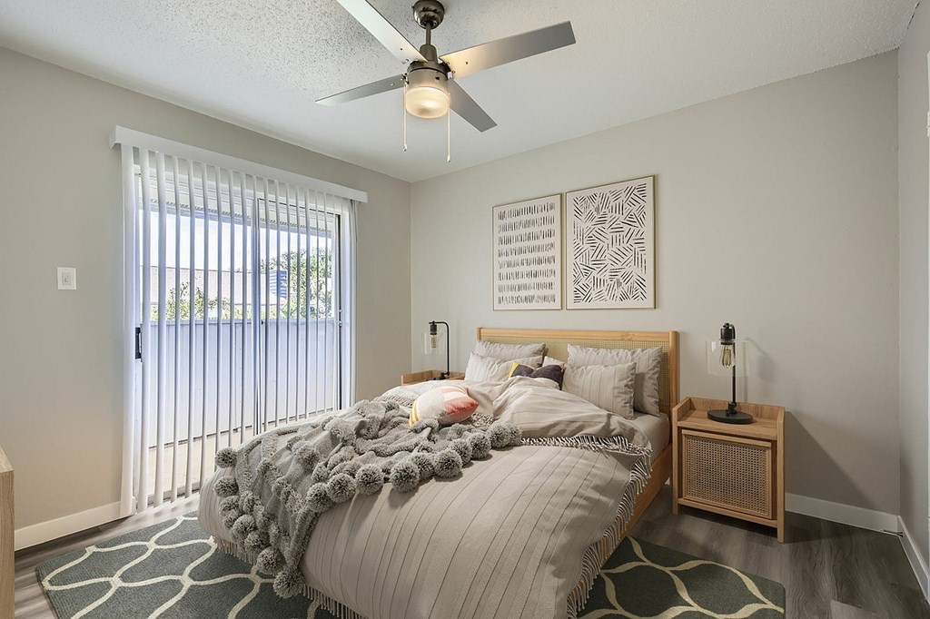 A bedroom with a bed, a nightstand, and a ceiling fan.