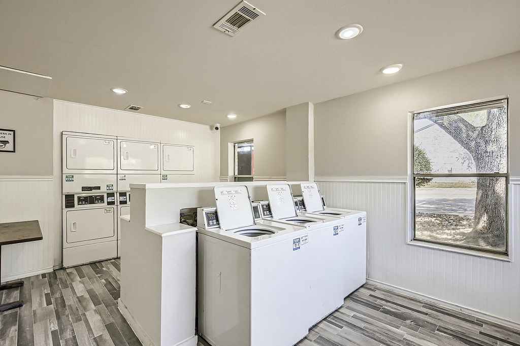 A white kitchen with a white counter and a white fridge.
