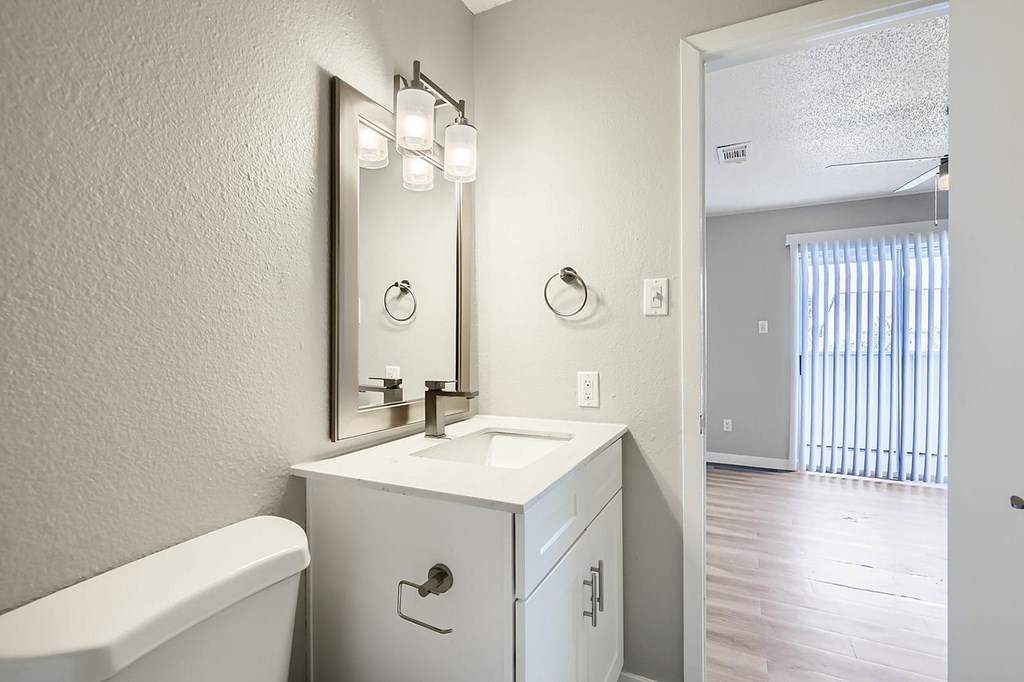 A white bathroom with a sink, mirror, and bathtub.