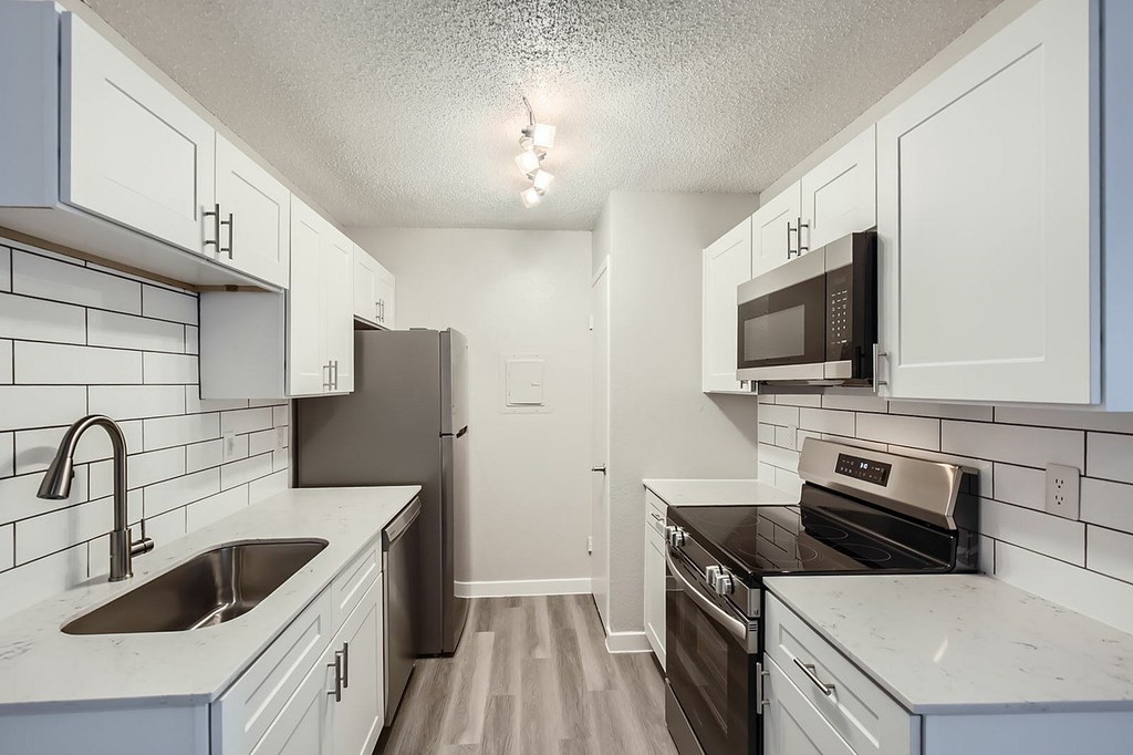 A kitchen with white cabinets and a black fridge.
