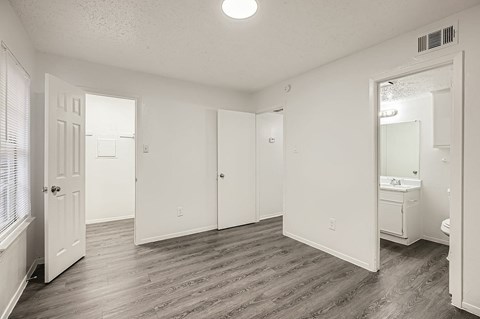 A spacious bathroom with a sink, mirror, and wooden flooring.