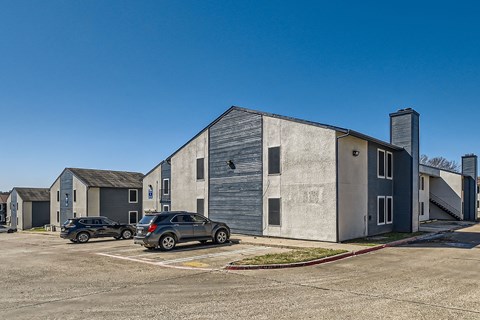 A parking lot with cars and a large building in the background.