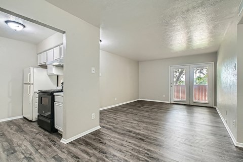 A kitchen area with a refrigerator, oven, and a window with blinds.