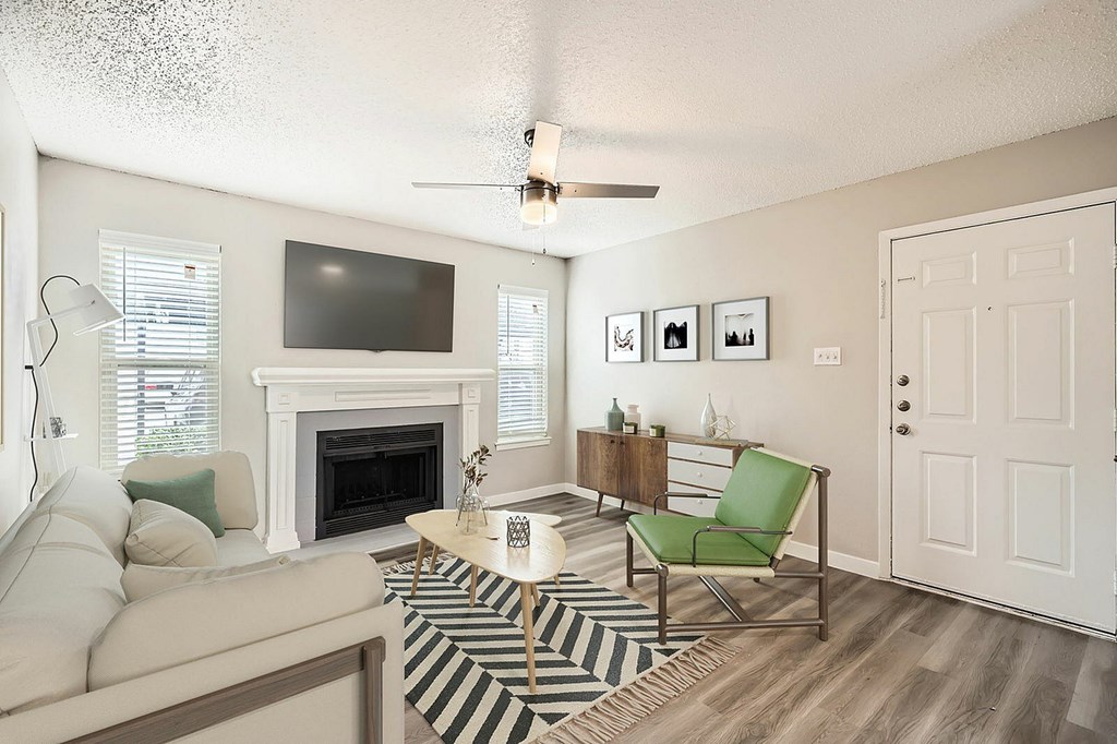 A living room with a fireplace, a couch, a chair, and pictures on the wall.
