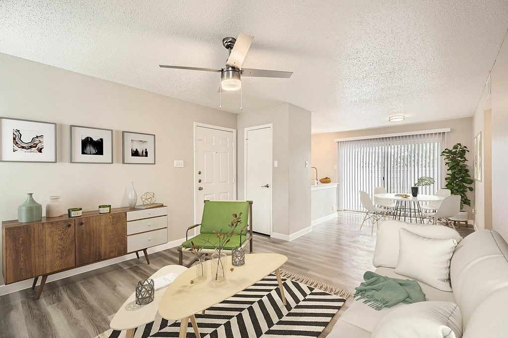 A living room with a white couch, a green chair, and a rug with black and white stripes.