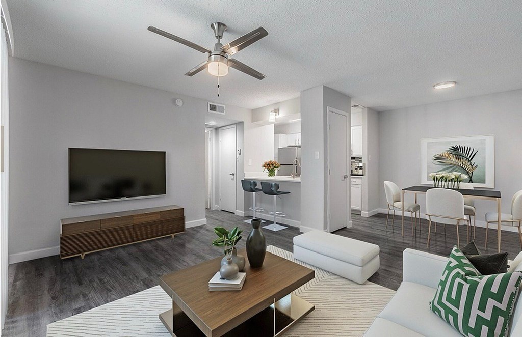 A modern living room with a flat screen TV, a coffee table, and a dining area.