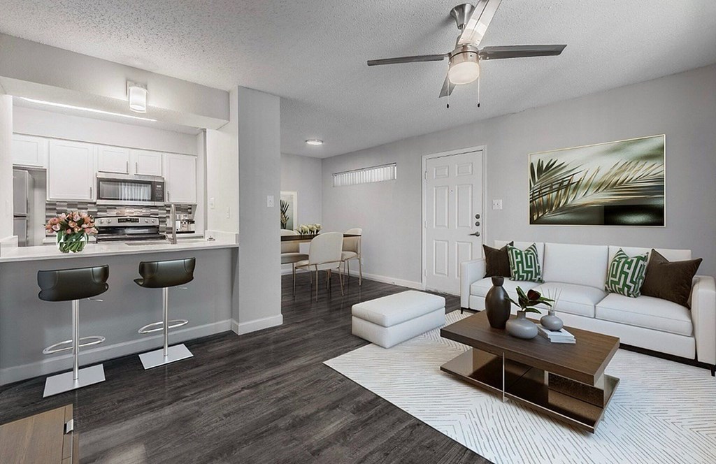A modern living room with a bar area and a ceiling fan.