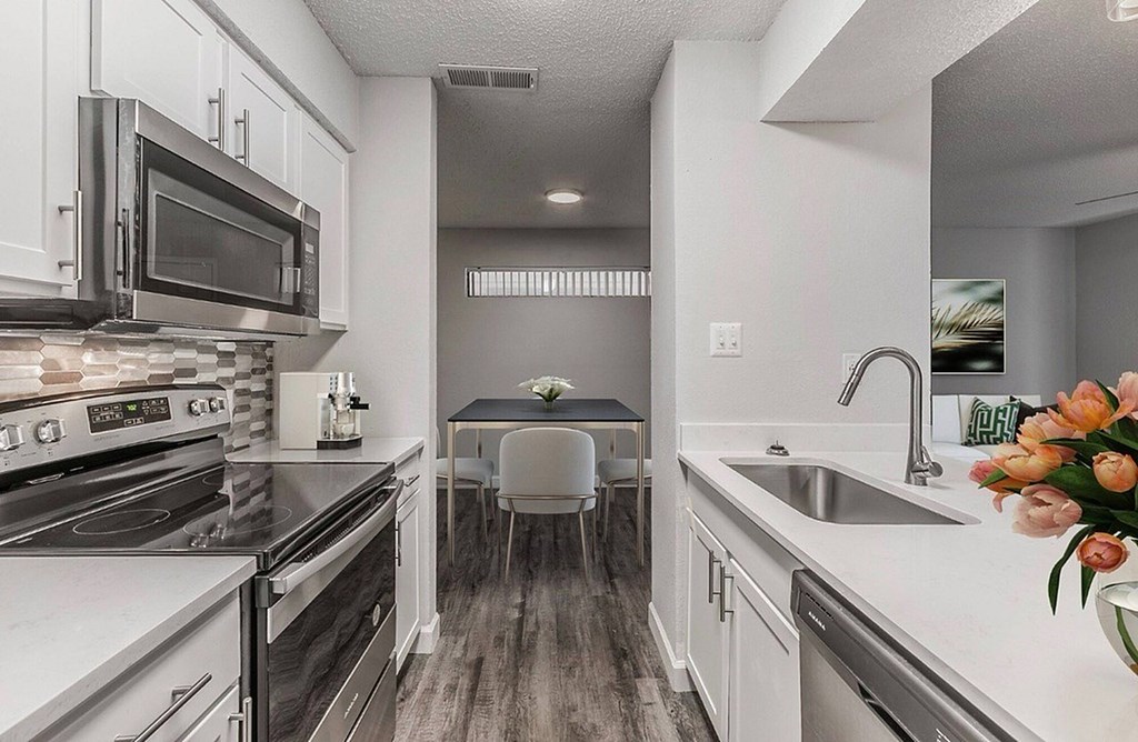 A kitchen with a stove, microwave, and sink.