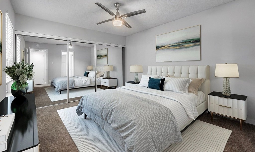 A bedroom with a large bed and a ceiling fan.