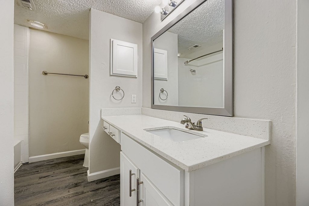 A white bathroom with a toilet, sink, and mirror.