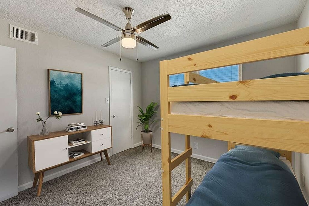 A bedroom with a bunk bed and a ceiling fan.