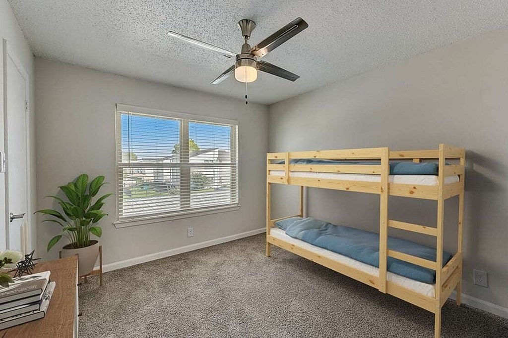 A room with a bunk bed and a ceiling fan.
