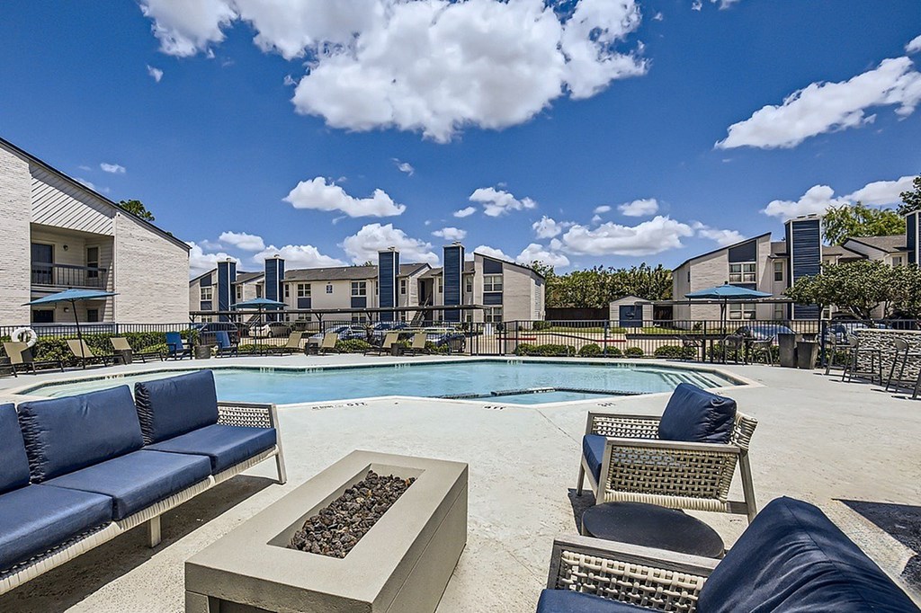 A pool area with a fire pit and lounge chairs.