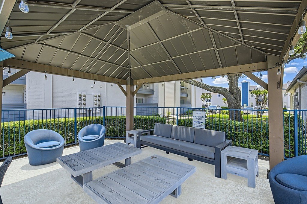 A patio with a grey sofa, two chairs and a table.