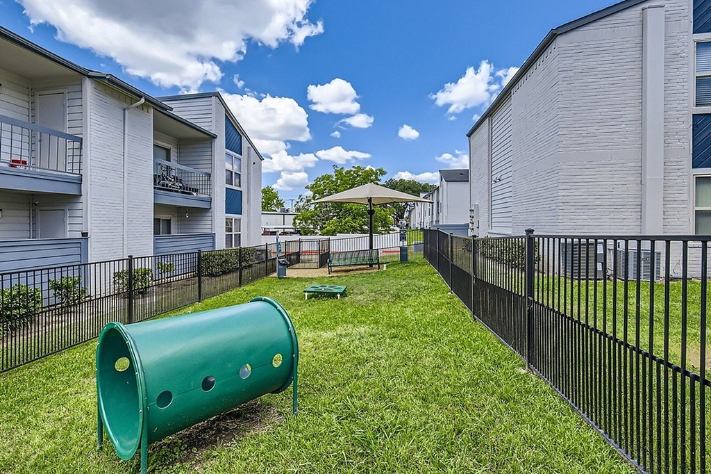 A playground with a green slide and a black fence.