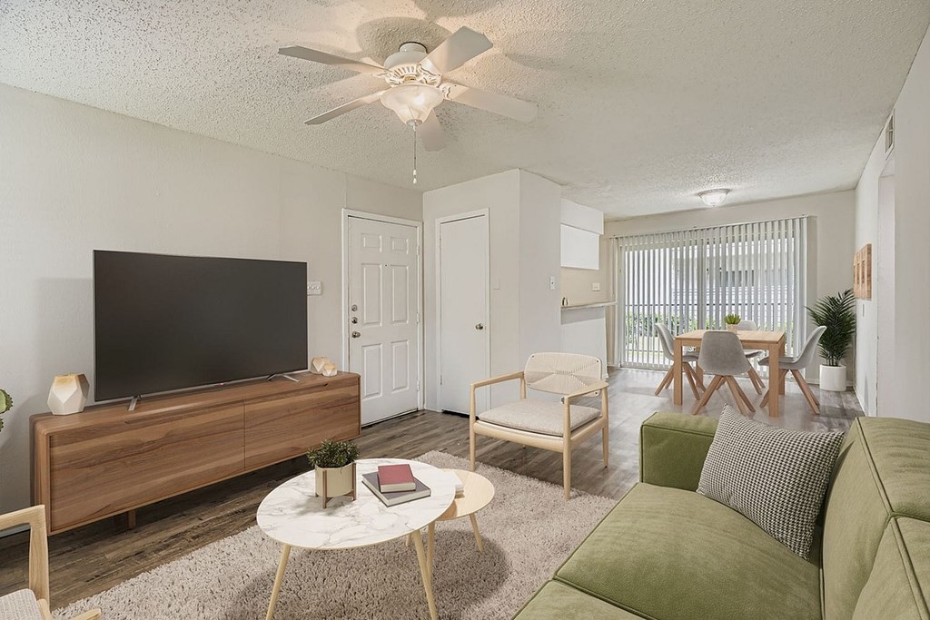 A living room with a green couch, a white coffee table, and a flat screen TV.