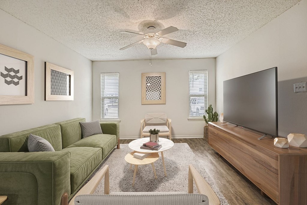 A living room with a green couch, a coffee table, and a flat screen TV.