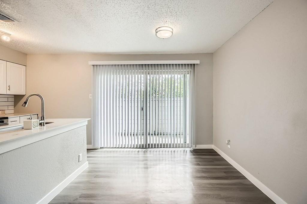 A kitchen with a sink and a window with blinds.
