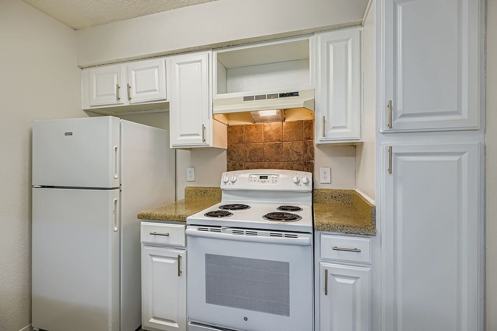 A white kitchen with a stove and refrigerator.