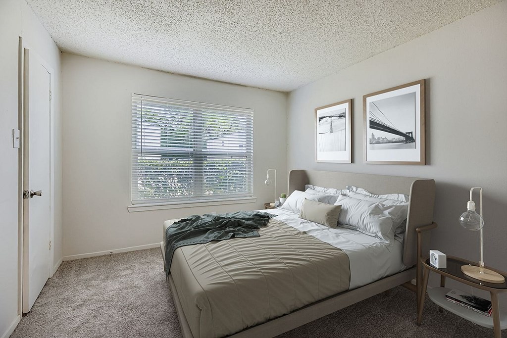 A bedroom with a bed, nightstand, and two pictures on the wall.