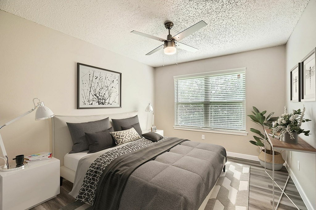 A bedroom with a bed, a ceiling fan, and a window with blinds.