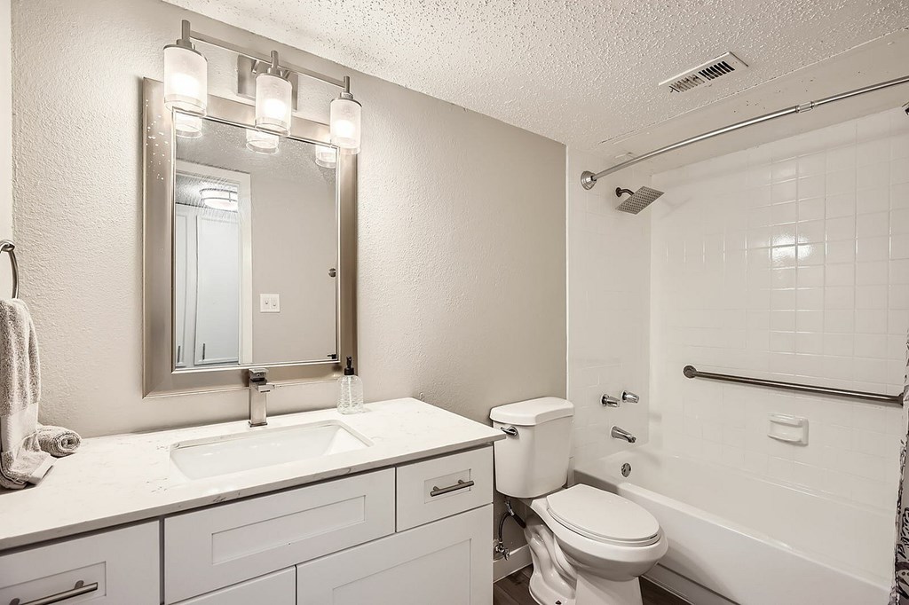 A white bathroom with a sink, toilet, and mirror.