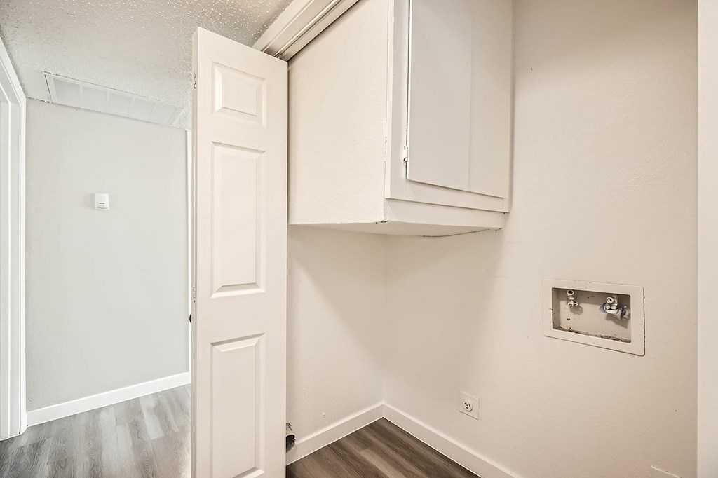A white door is open to a room with a white wall and a white cabinet.
