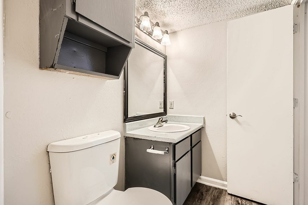 A bathroom with a toilet, sink, and cabinet.
