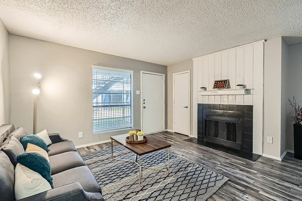 A living room with a grey couch and a fireplace.