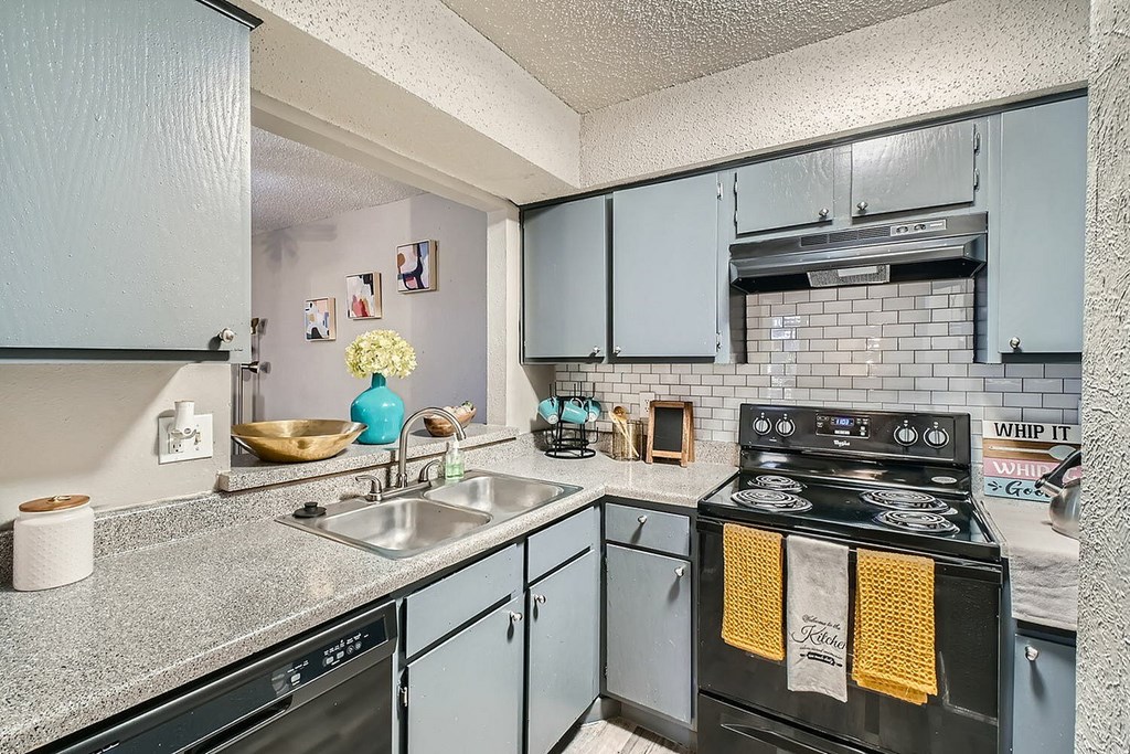A kitchen with a black stove top oven and grey cabinets.