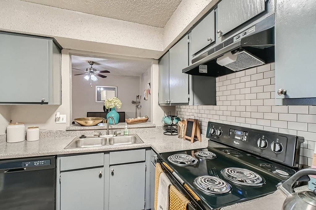 A kitchen with a black stove top oven and grey cabinets.