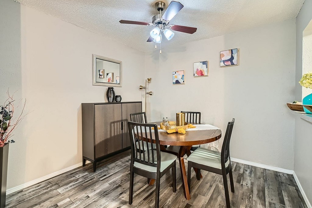 A dining room with a table set for two and a ceiling fan.