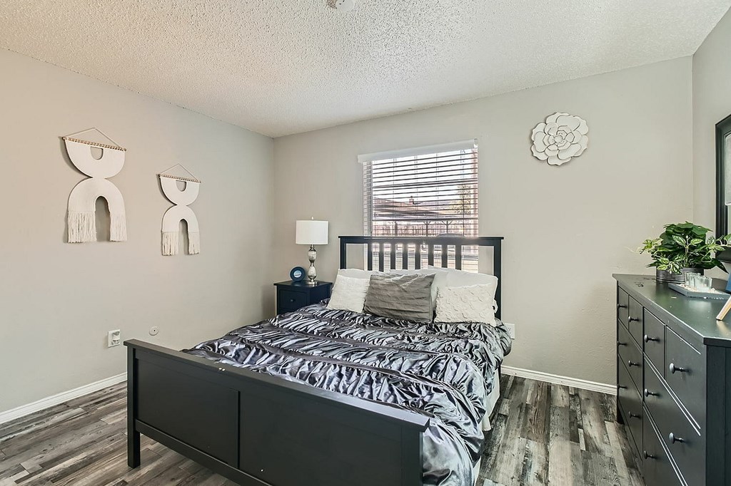 A bedroom with a bed, nightstand, and two decorative figures on the wall.