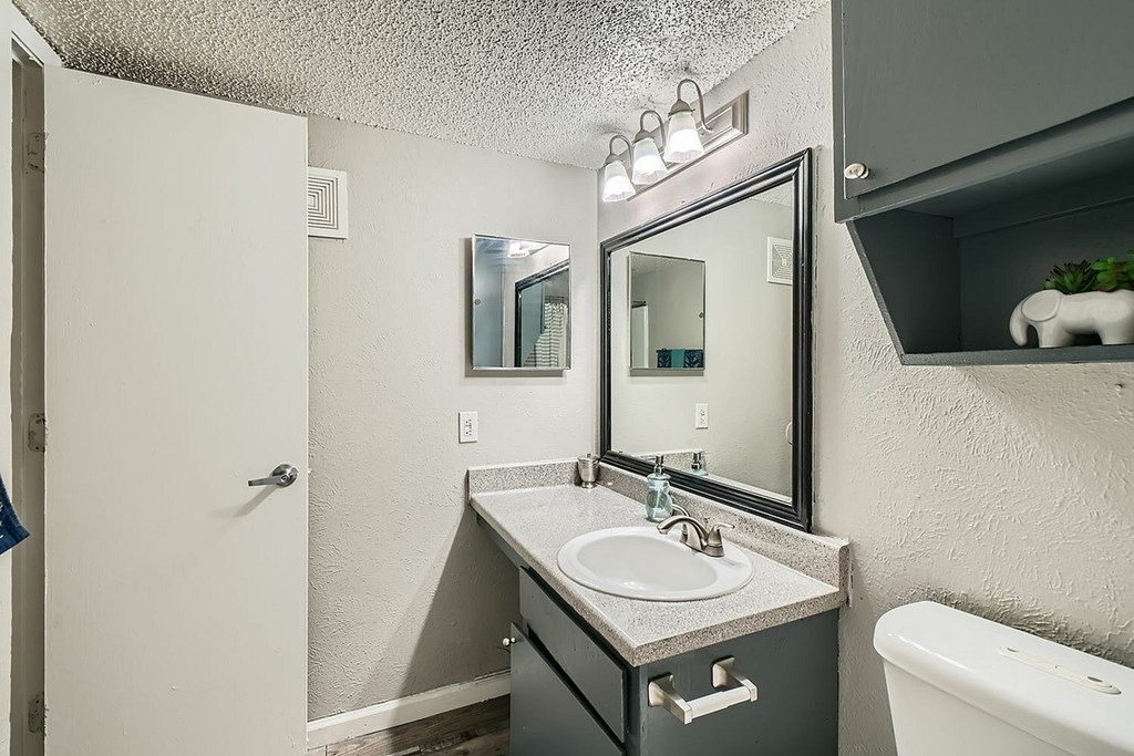 A bathroom with a sink, mirror, and a white bathtub.
