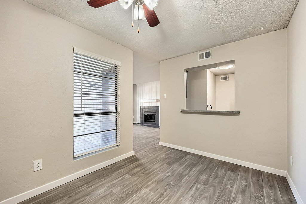 A room with a ceiling fan and a window with blinds.