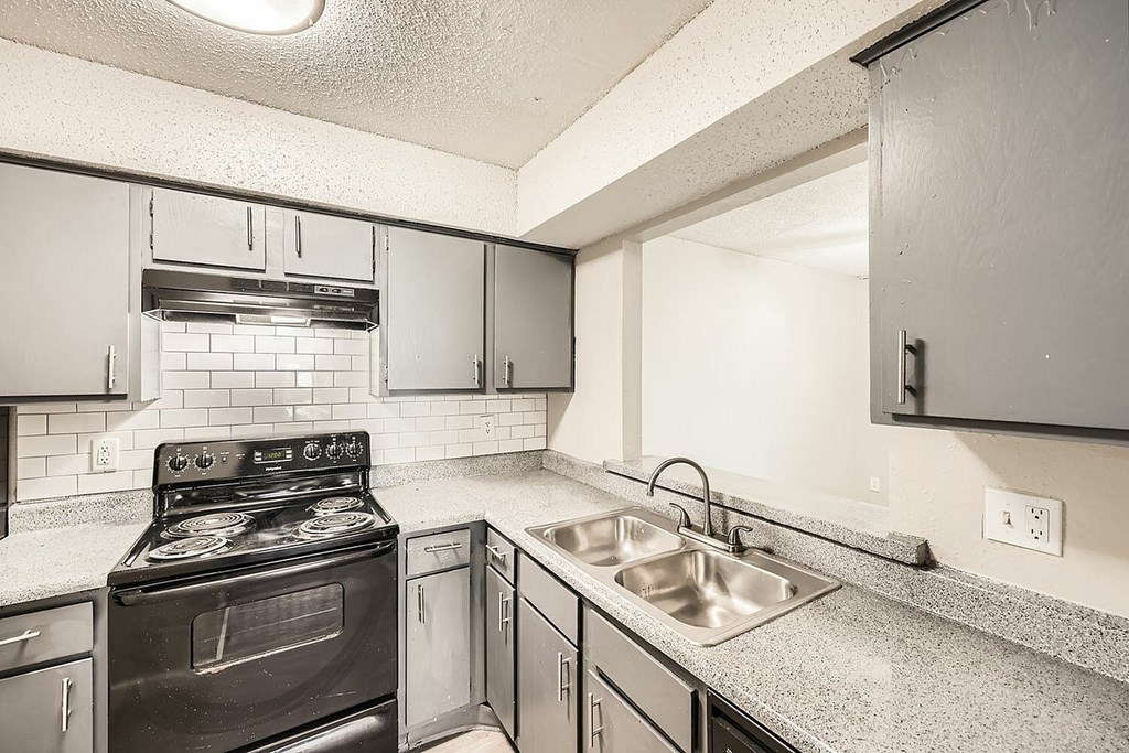 A kitchen with a black stove top oven and a stainless steel sink.